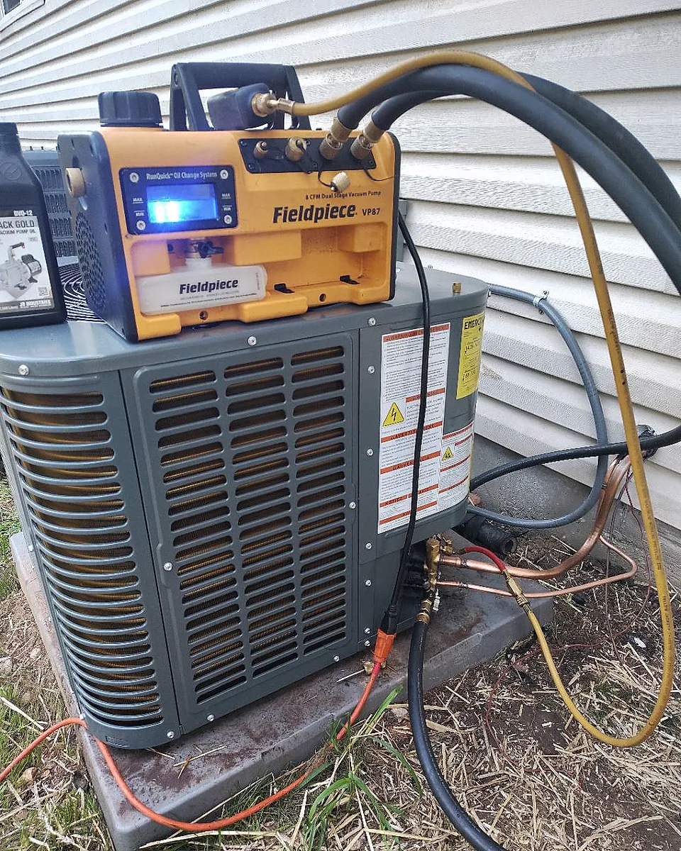 Vacuum pump and service hoses set up at outdoor HVAC equipment